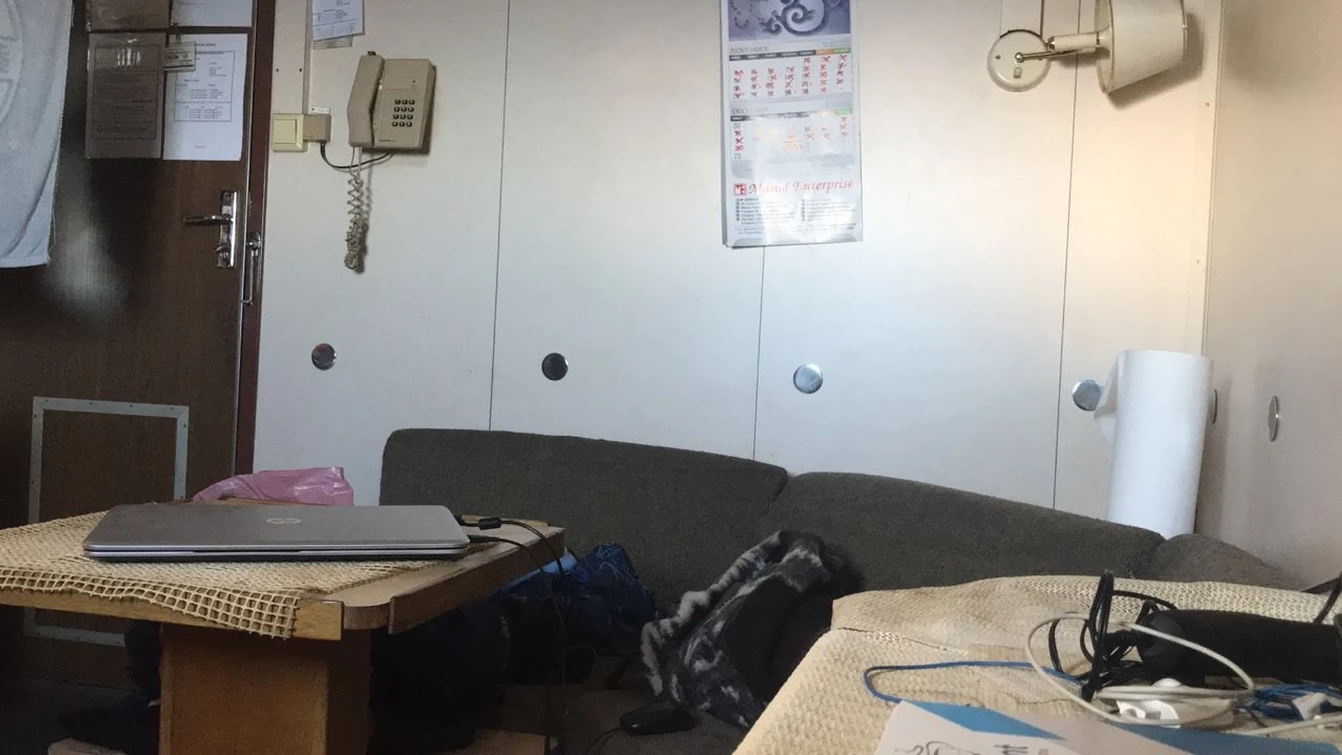A laptop open on a bunk in a small ship cabin at night